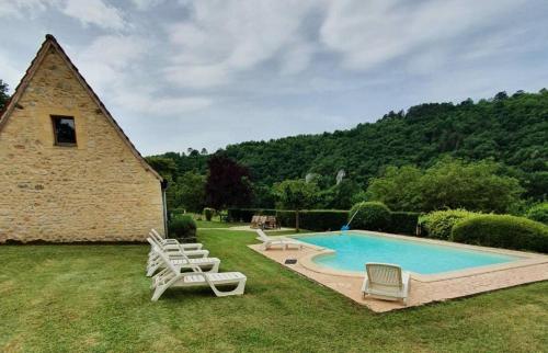 une piscine avec des chaises longues et un bâtiment dans l'établissement Les Maisons de Marzac, à Tursac