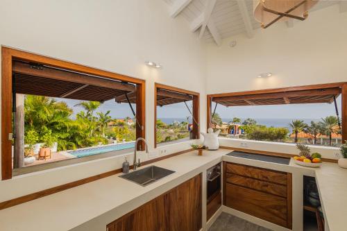 a kitchen with windows and a counter with a sink at Villa Shelu in Willibrordus