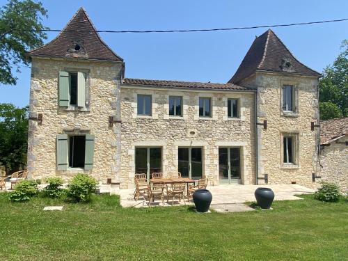 a large stone building with a table and chairs at Manoir des 2 Sources in Monestier