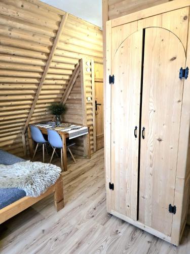 a room with a table and a bed and a wooden wall at Grota zbójnicka apartament i pokoje in Gliczarów