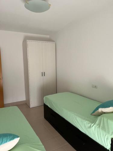 a bedroom with two beds and a white wall at Vacaciones en la playa in Sant Carles de la Ràpita