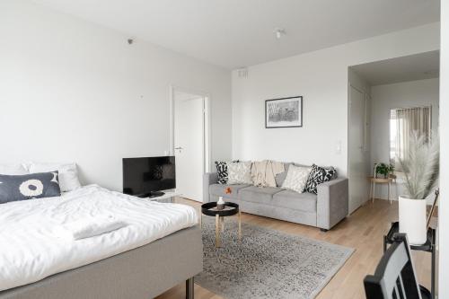 a white bedroom with a bed and a couch at "Pyynikinkulma" - 1BR Apt with Stunning Views, Sauna & Balcony in Tampere