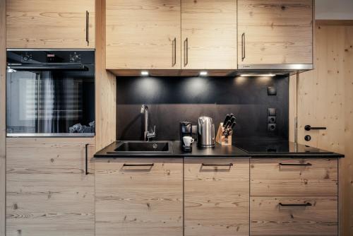 a kitchen with a sink and wooden cabinets at Leni Mountain Appartements in Sölden