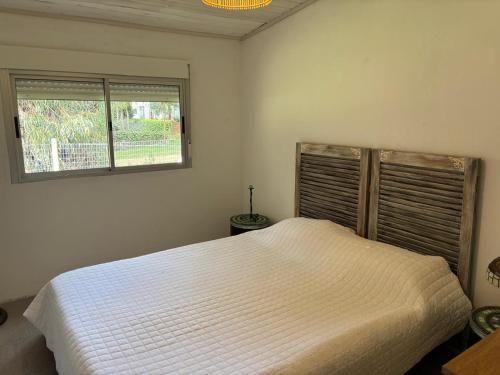 a bedroom with a white bed and a window at Casa completa Balneario Argentino in Balneario Argentino