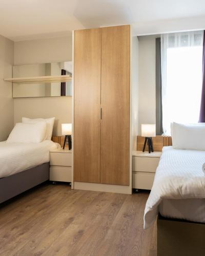 a bedroom with two beds and a wooden cabinet at Frezya - Exclusively Woman in Istanbul