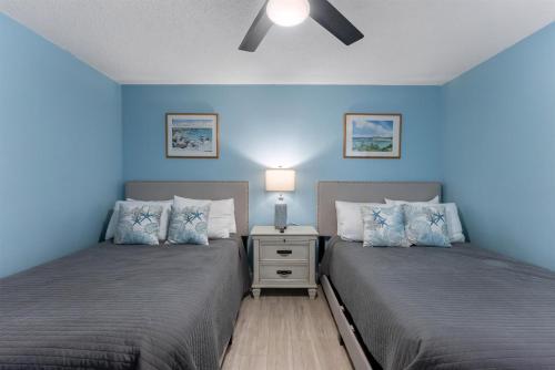 two beds in a bedroom with blue walls at 301 Ocean Ave, Unit 102 - The Harbor Light in North Wildwood