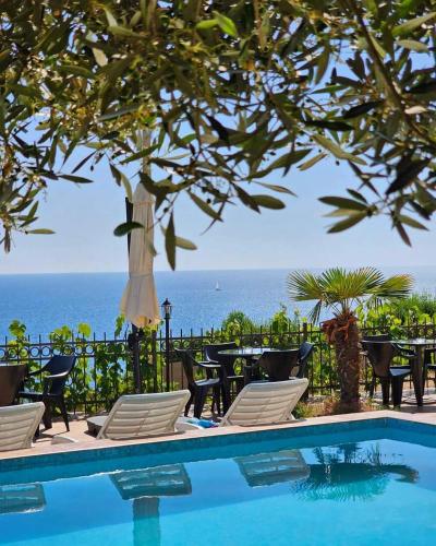 a pool with chairs and a table and the ocean at Open Sky Montenegro in Utjeha