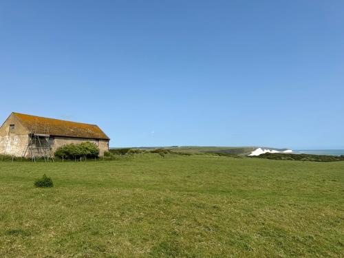 an old house in a field with the ocean in the background at Providence in Seaford in Seaford