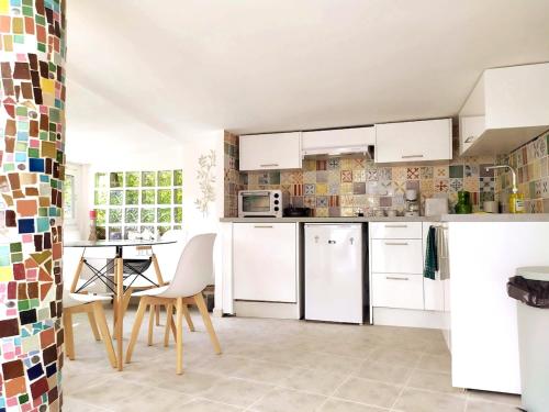 une cuisine avec des appareils blancs et une table avec des chaises dans l'établissement Cascade Esacapade Duplex, à Nice