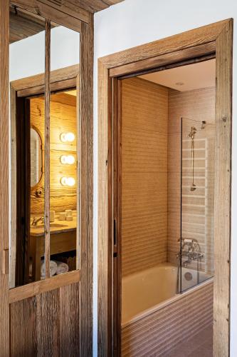 La salle de bains est pourvue d'une baignoire et d'une porte en verre. dans l'établissement Les Chalets de la Source 1 - Luxe - Skis aux pieds - 10 personnes, à Saint-Martin-de-Belleville