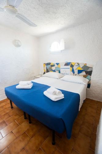 a bedroom with a blue bed with towels on it at Il Villaggio Del Mago in Lampedusa