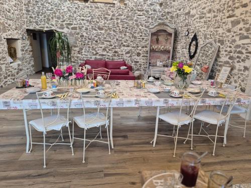 un grande tavolo con sedie e fiori sopra di Chambres d'hôtes LA GRANGE DU PA de LA GROLLE a Rocheservière