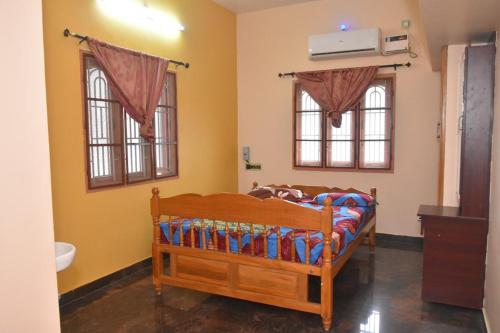 a bedroom with a bed and two windows at Royal Peters Holiday Homes, Main Falls, Coutralam in Kuttālam