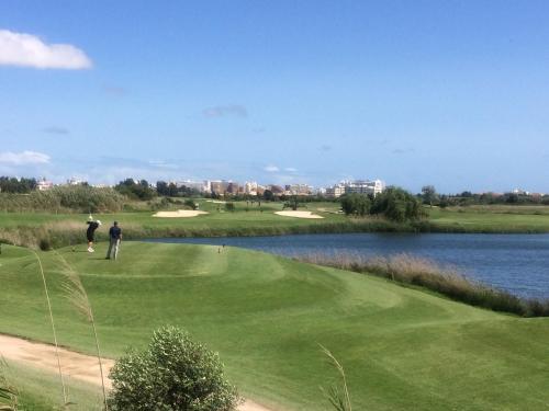 a man standing on a golf course next to a lake at Moura 11 in Vilamoura