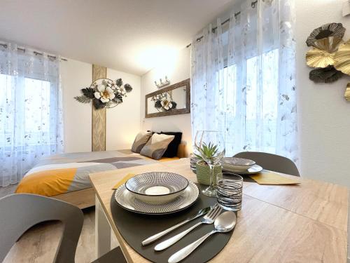 - une chambre avec un lit et une table avec des assiettes et de l'argenterie dans l'établissement L 'Éclat Doré - Studio - Proche Gare - 2 P, à Belfort
