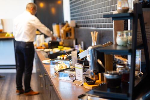 a man standing in a kitchen preparing food at Hotel FÜNF10 in Netphen