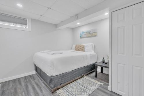 a white bedroom with a bed and a door at Luxury Basement Suite in Top Prime Location in Winnipeg