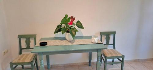 a blue table with a vase of flowers on it with two chairs at Izabella Studios Apartments in Pitsidia