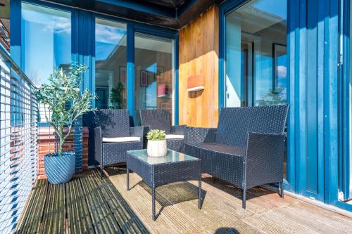 a patio with chairs and a table and windows at Waterfront Penthouse with Balcony & Parking in Liverpool
