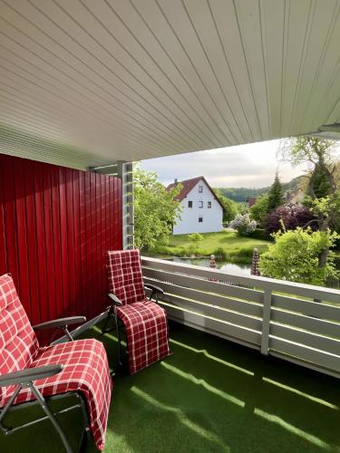 two chairs on a porch with a view of a house at Ferienwohnung an der Lauter in Indelhausen