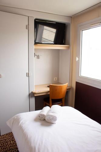 a bedroom with a bed and a desk and a window at Hôtel Les Genêts Bayonne in Bayonne