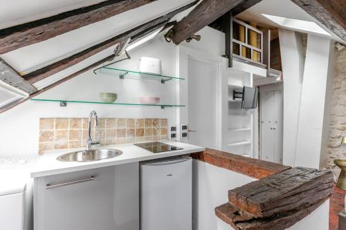 une cuisine avec des armoires blanches et un évier dans l'établissement Studio sous les poutres à Paris, à Paris
