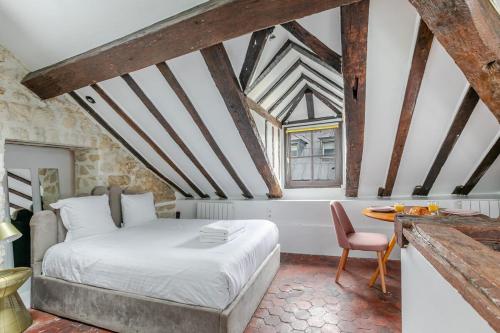 une chambre avec un lit et une table avec une chaise dans l'établissement Studio sous les poutres à Paris, à Paris