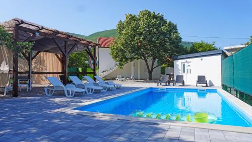 a swimming pool with chaises and chairs next to a building at Twins Land in Mostar