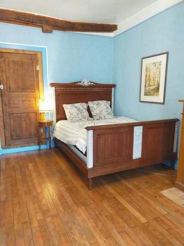 a bedroom with a bed with blue walls and wooden floors at maison médiéval pour six personnes in Saint-Benoît-du-Sault