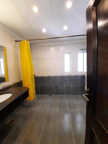 ein Badezimmer mit Waschbecken und gelbem Vorhang in der Unterkunft Royal Crown in Islamabad