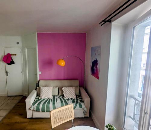 Cette chambre comprend un lit et un mur rose. dans l'établissement Appartement cosy Batignolles, à Paris