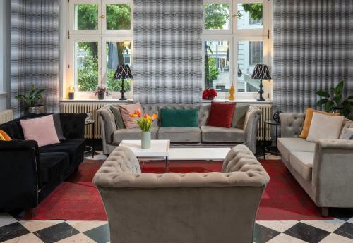 a living room with couches and a table and windows at SORAT Hotel Cottbus in Cottbus