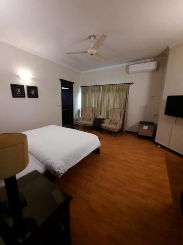 ein Schlafzimmer mit einem weißen Bett und ein Wohnzimmer in der Unterkunft Royal Crown in Islamabad