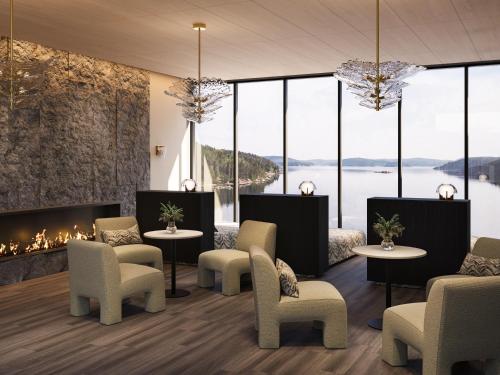 a lobby with a fireplace and chairs and windows at Vann Spa Hotell & Konferens in Brastad