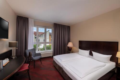 a hotel room with a bed and a desk and a window at SORAT Hotel Cottbus in Cottbus