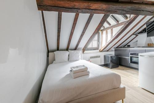 une chambre avec un lit blanc dans un grenier dans l'établissement Studio cosy pour 2 au cœur de Paris, à Paris