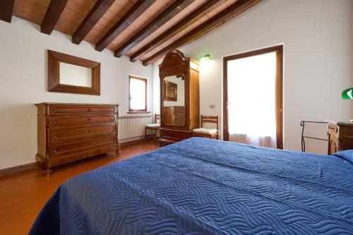 a bedroom with a blue bed and a dresser and a window at Poggio Diavolino - Suvereto in Suvereto