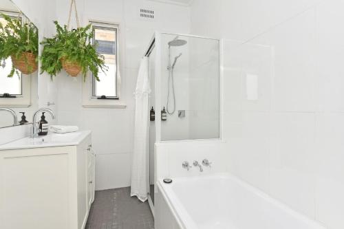 a white bathroom with a tub and a sink at The Little Lake House Waterfront Escape in Rathmines