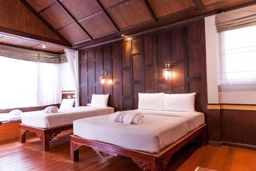 two beds in a room with wooden walls at Coco Palm Beach Resort - SHA Extra Plus in Mae Nam