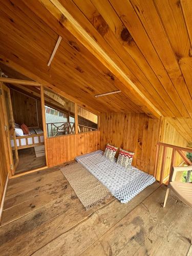 a room with a bed in a wooden cabin at Baserah - Stay & Cafe in Jibhi