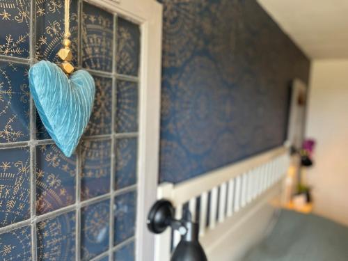 a blue heart hanging on a wall next to a window at Gîte "La belle vie" in Chamblet