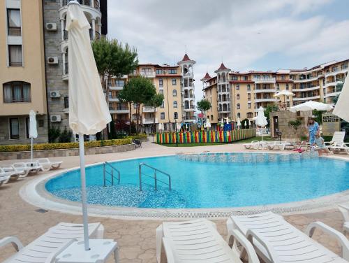 a large swimming pool with chairs and an umbrella at 2 Room Apartment with Poolview Royal Sun in Sunny Beach
