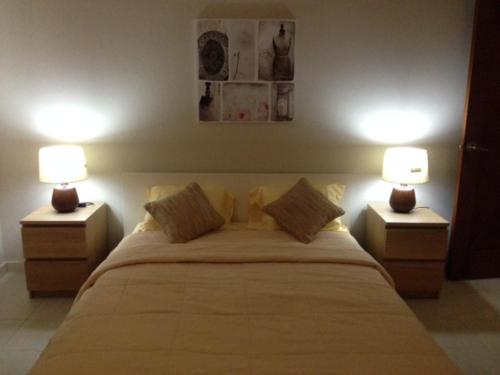 a bedroom with a large bed with two lamps at Villas Del Jardin 7 in Juan Dolio