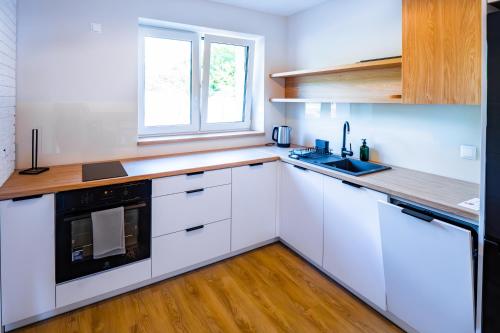 a kitchen with white cabinets and a sink and a window at Mazurskie Apartamenty "Jak Tu Miło!" in Węgorzewo