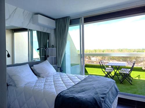 une chambre avec un lit et un balcon avec une table dans l'établissement Studio 18, Héliopolis L au village naturiste, au Cap d'Agde