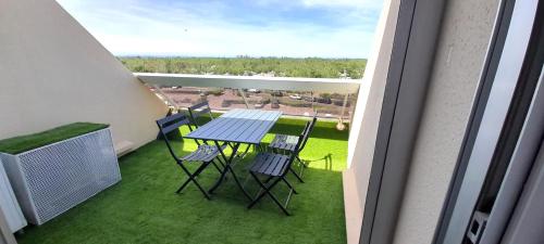 d'un balcon avec une table et des chaises sur gazon. dans l'établissement Studio 18, Héliopolis L au village naturiste, au Cap d'Agde