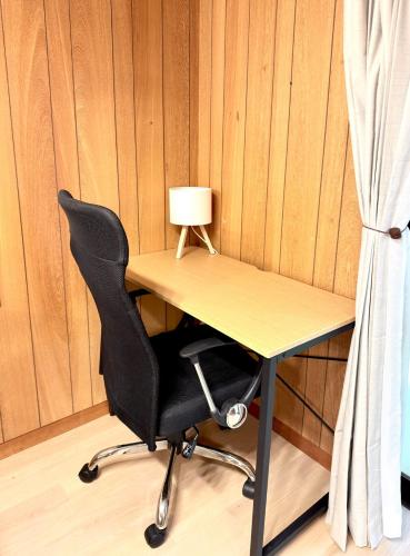 a desk with a chair and a lamp on it at ぽんぽこハウス in Tokoname