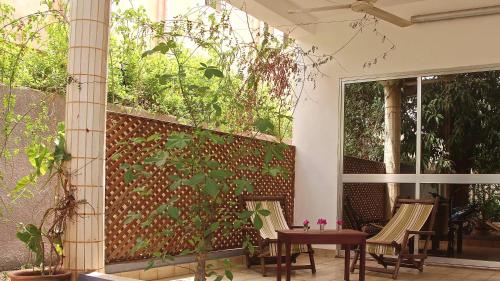 a patio with chairs and a fence with plants at B & B Le Nomade in Ouagadougou