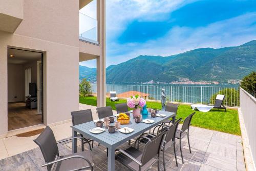 a table and chairs on a patio with a view of the water at Spa Stella Lario in Lezzeno