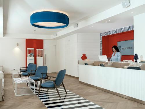 a woman standing at a counter in a waiting room at Hotel Tirrenia in Sorrento